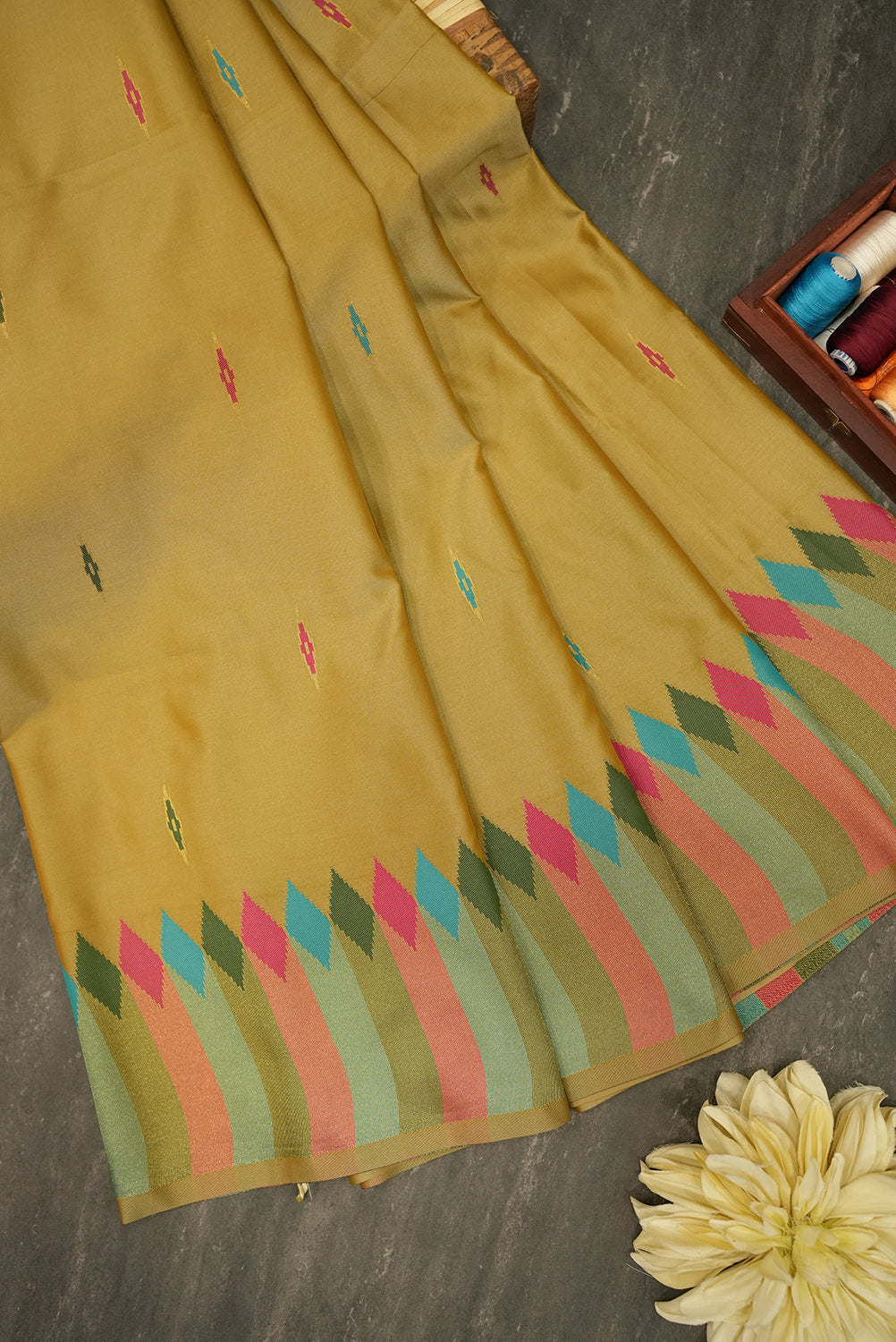 Yellow saree with colorful patterns on a dark surface